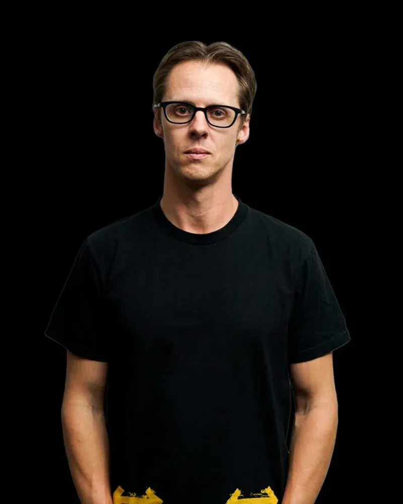 Actor headshot, man in glasses and a black t-shirt on black